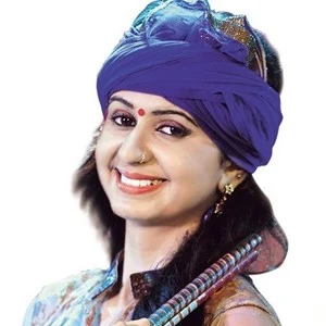 Kinjal Dave smiling, in a blue turban and traditional dress.