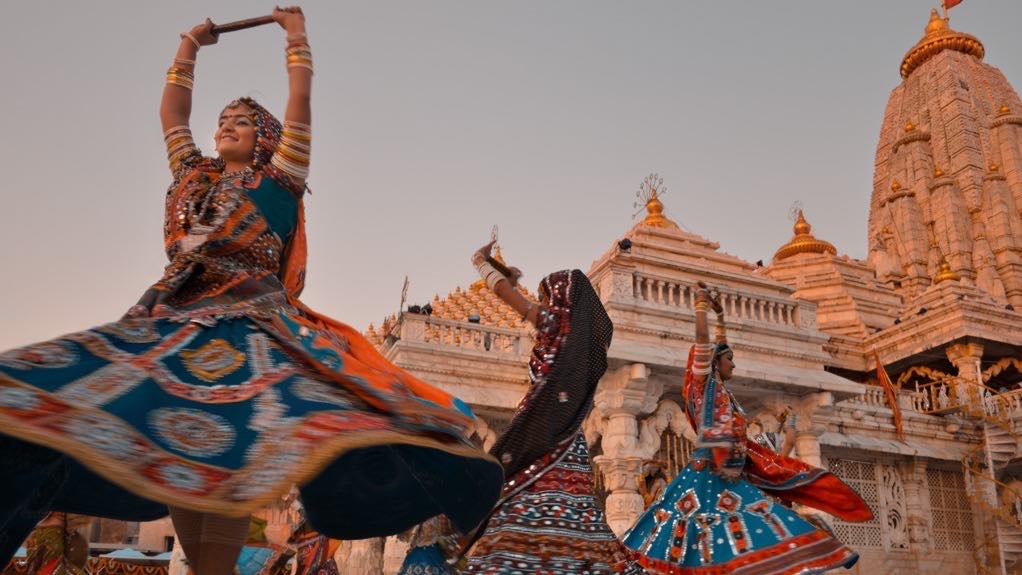 Dandiya dancers mid-spin in front of the Ambaji temple at sunset